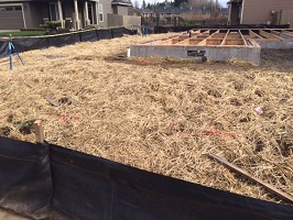 Straw and silt fencing used to cover bare soil and control erosion at a residential construction site.