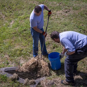 two men clearing debris from field inlet 