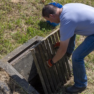 man at field inlet removing grate