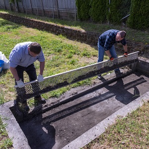 Two men removing a trash screen.