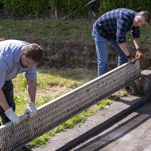 Two men replace a trash screen.